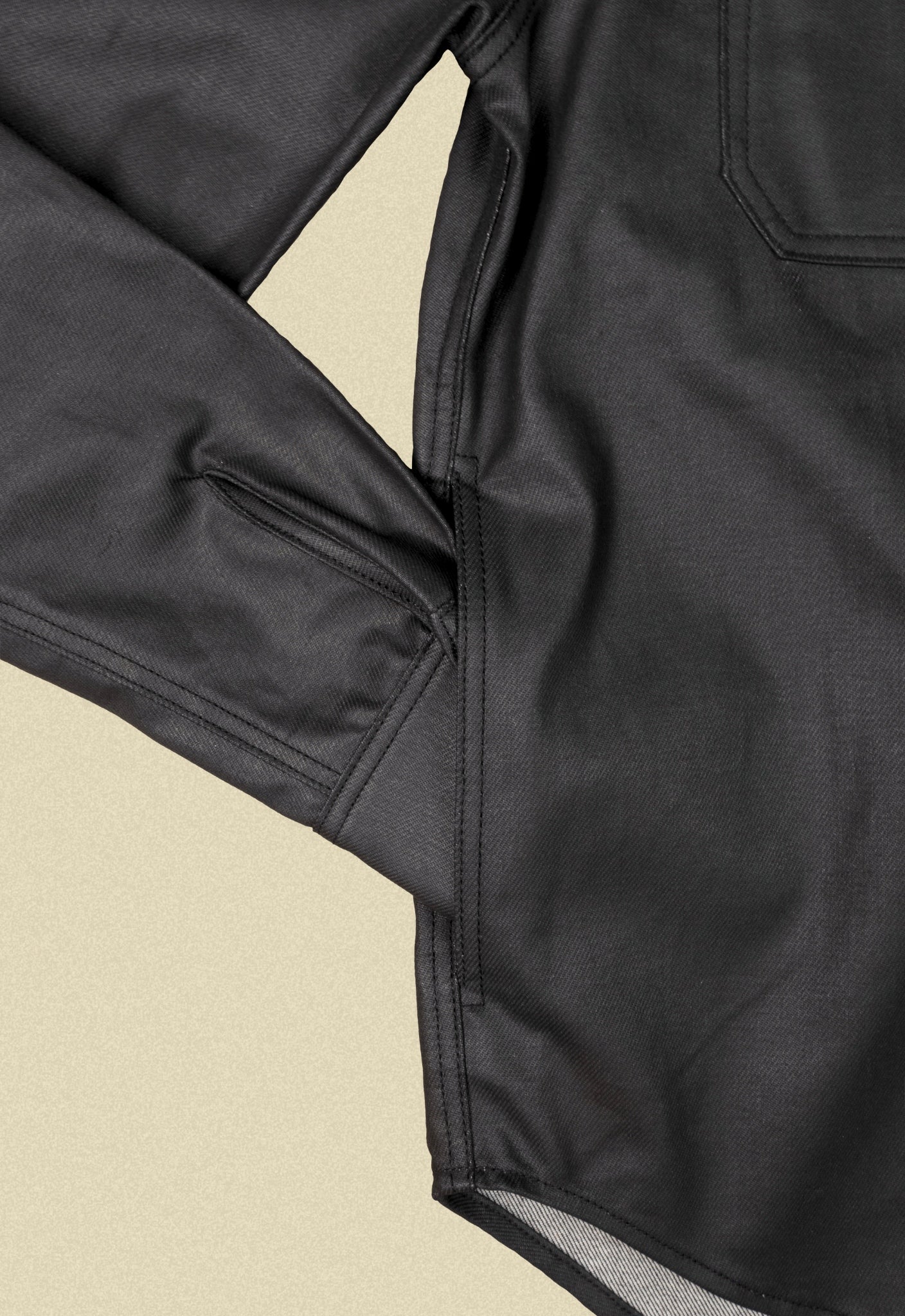 Close up of a black denim button-up chore shacket on a beige background