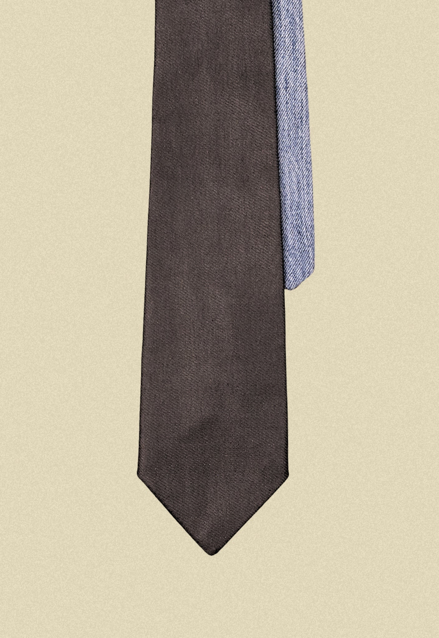 Repurposed coated black and blue denim tie on a beige background